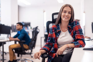 Casual businesswoman working on a desktop computer in modern open plan startup office interior. Selective focus. High-quality photo